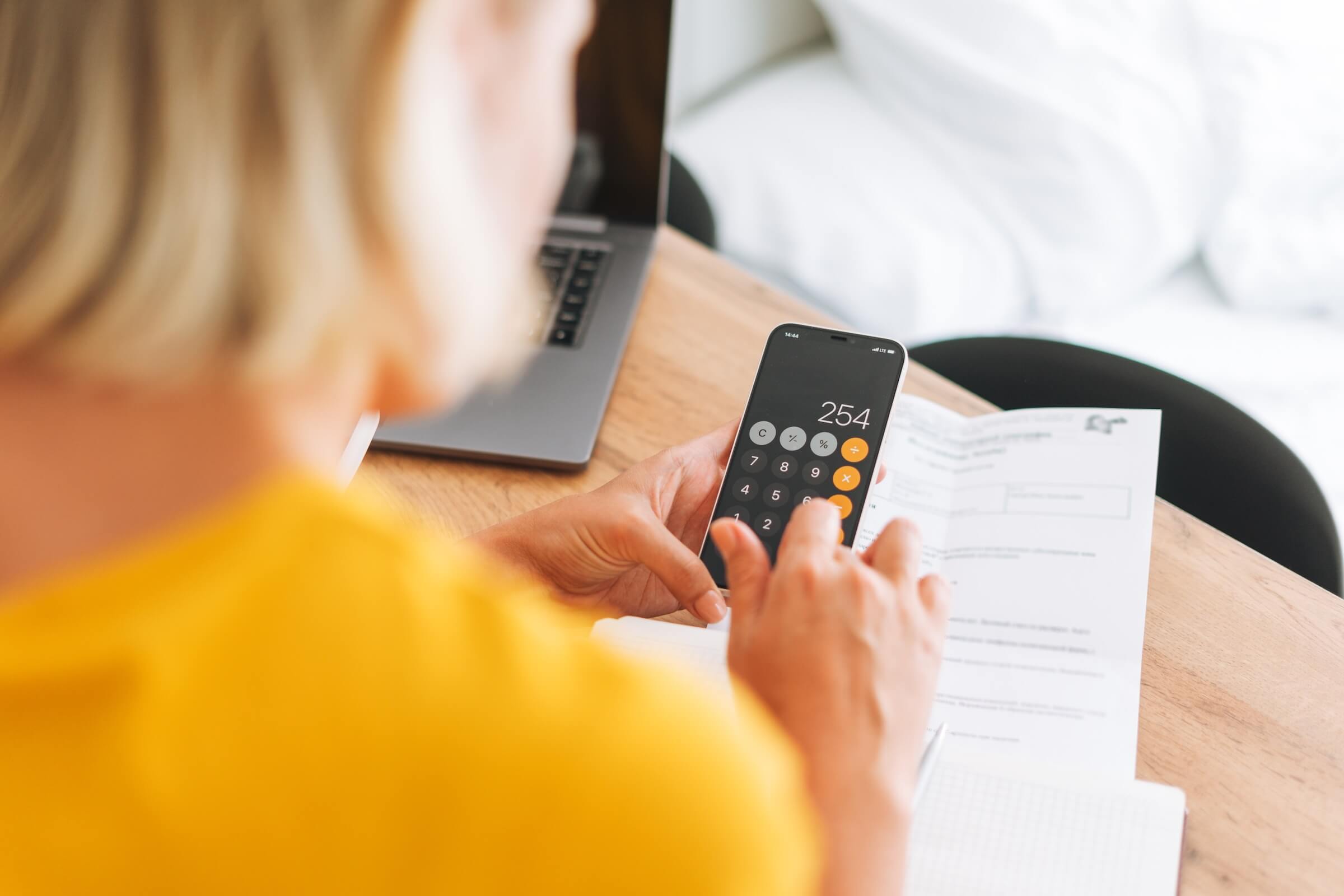 Woman using calculator app on phone to calculate rent price