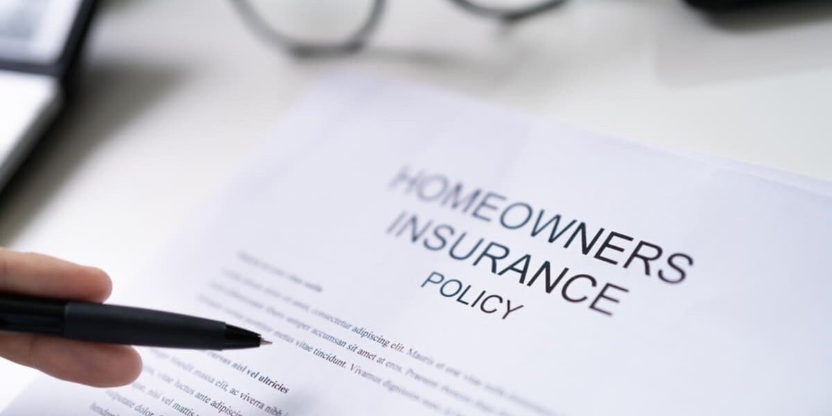 Close-up of a hand with a pen and homeowners insurance policy - featured_image