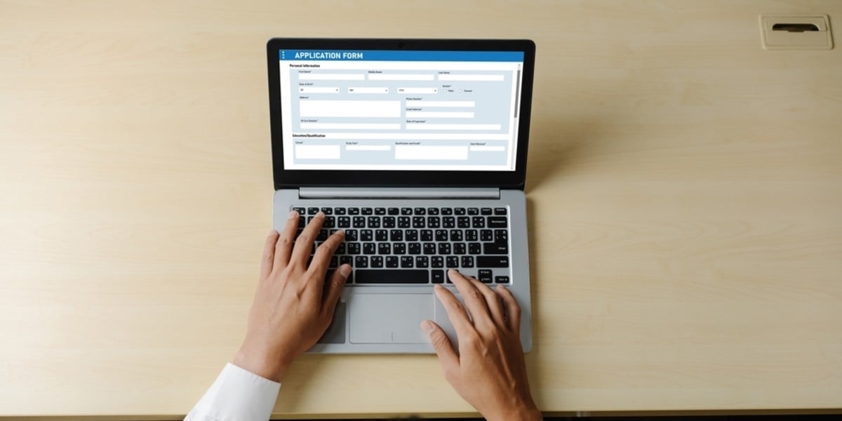 An application form on a laptop screen on a desk