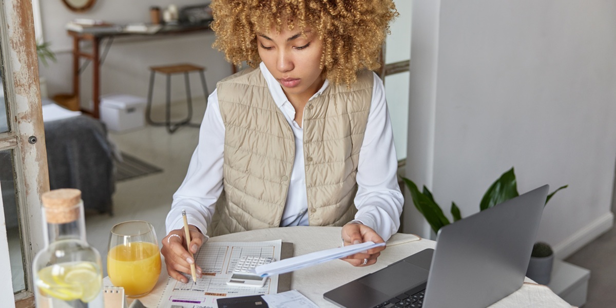 Woman sitting at a table with a calculator making a budget