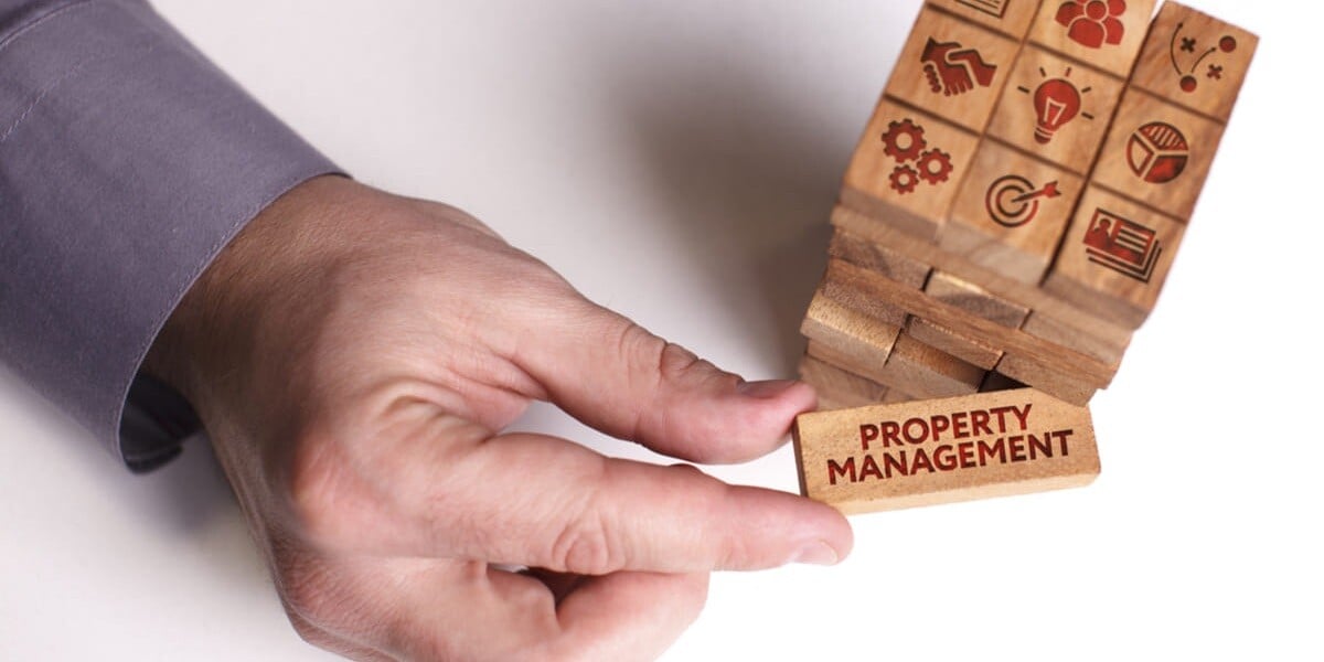 holding a wood block labeled property management